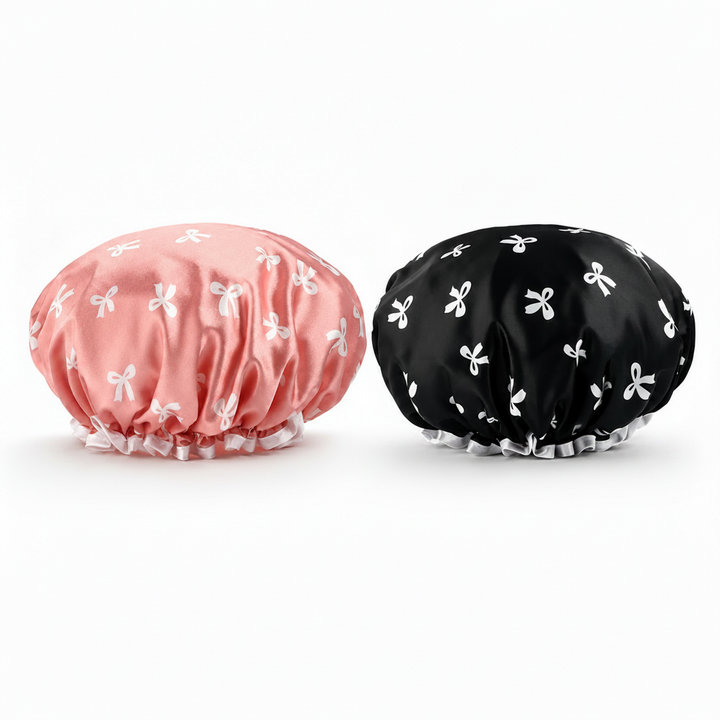Pink and black satin shower caps flat lay on white background